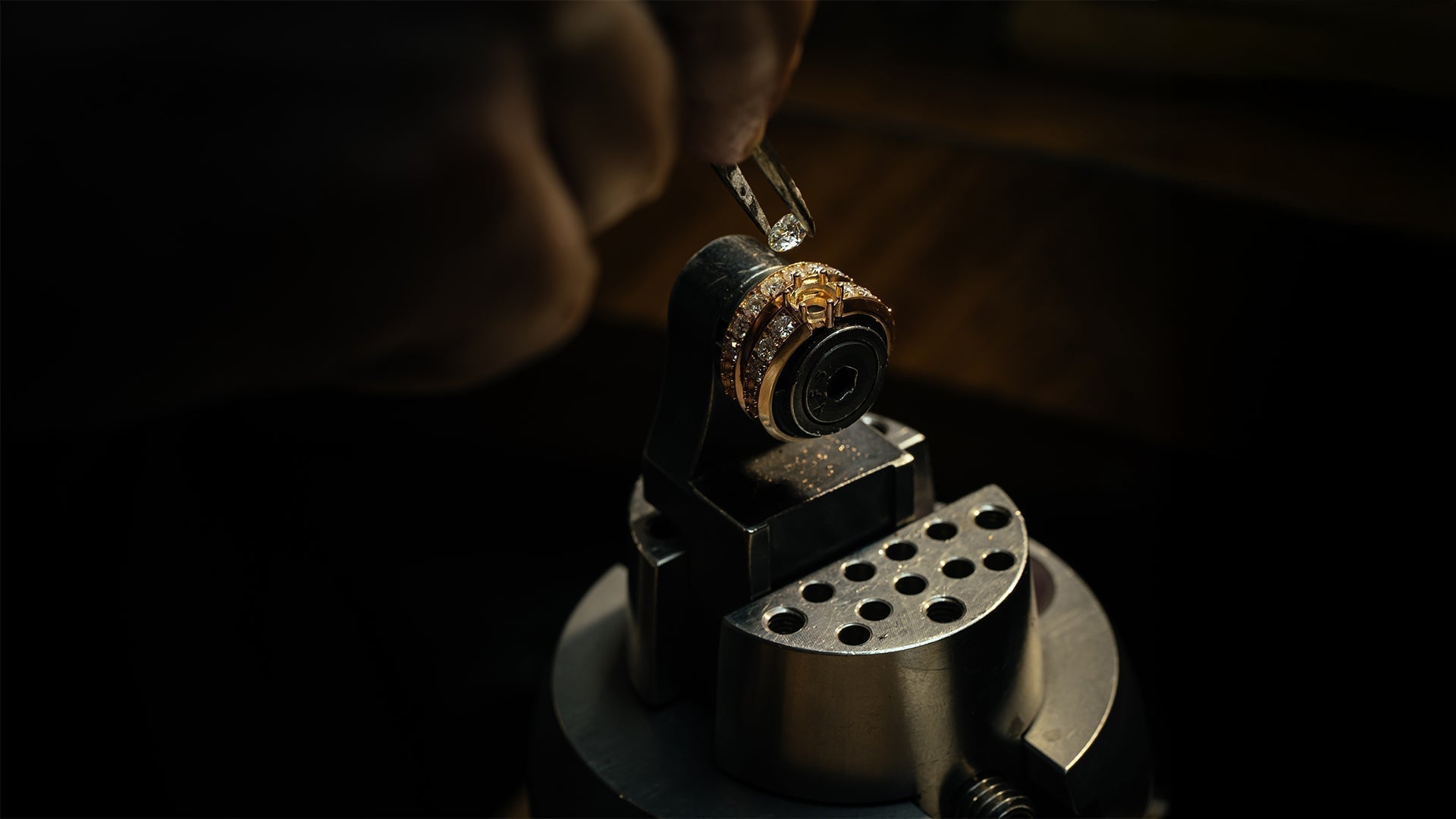 Image of a craftsman carefully adjusting a diamond on a gold ring during the remodelling process.