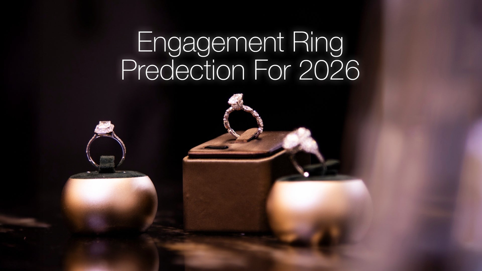 Three diamond engagement rings displayed on gold and brown velvet stands with text overlay reading 'Engagement Ring Prediction'. For 2026 against a dark, moody background.